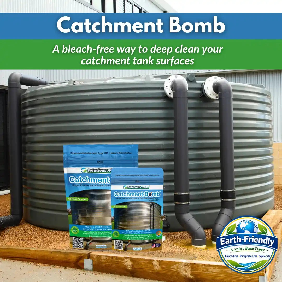 A large gray corrugated metal catchment tank with black pipes on a wooden deck, alongside two retail packages of Catchment Bomb.