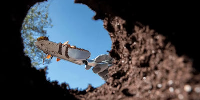 Small airplane flying through a circular hole in the ground with a blue sky background